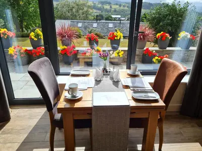 a wooden table with chairs and flowers on a window at Camden Lodge B&B and Cottage Brecon in Brecon