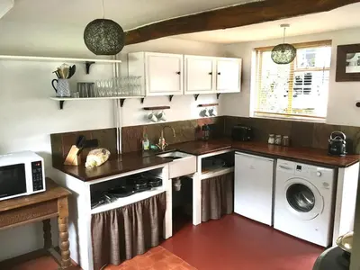 a kitchen with white cabinets and a washer and dryer at Chapel Cottage in Machynlleth