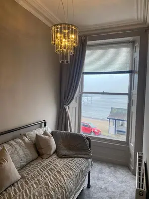 a bedroom with a couch and a window and a chandelier at Lan Y Môr 4 Aberystwyth in Aberystwyth