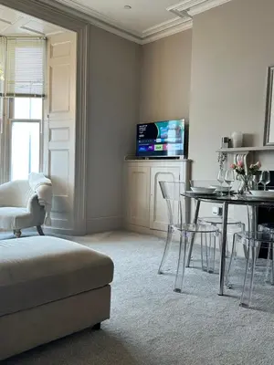a living room with a table and chairs and a television at Lan Y Môr 4 Aberystwyth in Aberystwyth