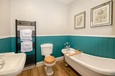 a bathroom with a tub and a toilet and a sink at Baskerville House in Clyro