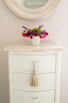 a white dresser with a vase with flowers on it at Baskerville House in Clyro