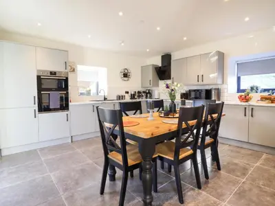 a kitchen and dining room with a wooden table and chairs at Tyn Llwyn Barn in Corwen
