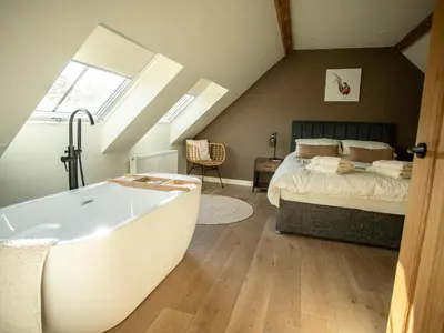 a bathroom with a bath tub next to a bed at Tyn Llwyn Barn in Corwen