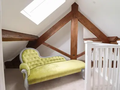 a yellow chair in a room with a crib at The Clockhouse in Llandyssil
