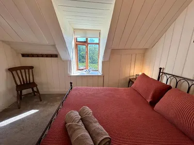 a red bed in a room with a window at Panoramic Mountain Retreat - Waen Fechan - 4x4 access only in Dolgellau