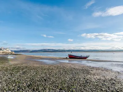 a boat sitting on the shore of a beach at Pebble Cottage in Aberdyfi