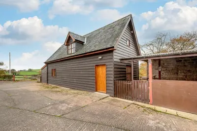 a gray house with a brown door and a brick building at 2 Bed in Y Drenewydd oc-waa401 in Llanllugan
