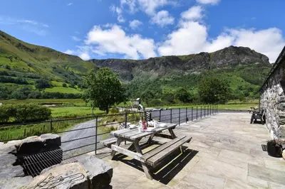 a picnic table on a patio with mountains in the background at 4 Bed in Dinas Mawddwy oc-bow305 in Aber Cowarch