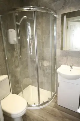 a bathroom with a shower and a toilet and a sink at Leahurst Bed and Breakfast in Tywyn