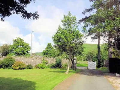 a park with a tree in the middle of a field at Leahurst Bed and Breakfast in Tywyn