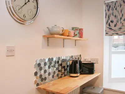 a kitchen with a counter with a clock on the wall at Pippin's Place in Shrewsbury