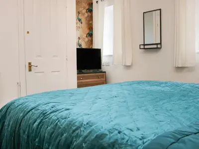 a bedroom with a blue bed and a television at Pippin's Place in Shrewsbury