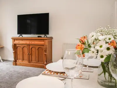 a living room with a table with flowers and a tv at Pippin's Place in Shrewsbury