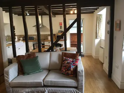 a living room with a couch and a kitchen at 200 year old Gardener's cottage, Mid Wales in Llanidloes