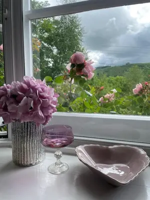 a table with a vase and a glass and a window at 200 year old Gardener's cottage, Mid Wales in Llanidloes