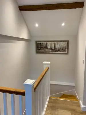 a white staircase with a painting on the wall at The Barn at Pentregaer Ucha, with tennis court and lake in Oswestry