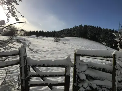 a fence covered in snow next to a snow covered field at The Barn at Pentregaer Ucha, with tennis court and lake in Oswestry