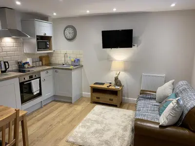 a living room with a couch and a kitchen at The Barn at Pentregaer Ucha, with tennis court and lake in Oswestry