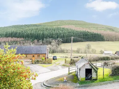 a small cabin with a hill in the background at Rhiw Gam in Abbey-Cwmhir