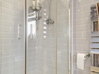 a bathroom with a shower with white tiles at Rhiw Gam in Abbey-Cwmhir
