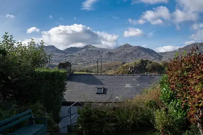 a view of a house with mountains in the background at Homely cottage with garden and mountain-view in Blaenau-Ffestiniog