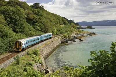 a train traveling down the tracks next to a river at 2 Bed in Y Drenewydd oc-waa402 in Llanllugan