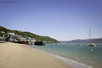 a beach with boats in the water next to a town at 2 Bed in Y Drenewydd oc-waa402 in Llanllugan