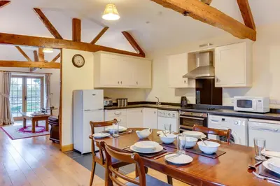 a kitchen with a wooden table with chairs and a kitchen with white cabinets at 2 Bed in Y Drenewydd oc-waa402 in Llanllugan