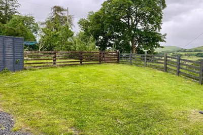 a wooden fence with a grassy yard at 3 Bed in Machynlleth oc-bow306 in Darowen
