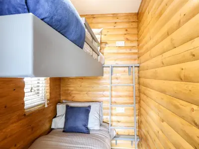 a small bedroom with wooden walls and a bunk bed at Hilltop Lodge in Corwen