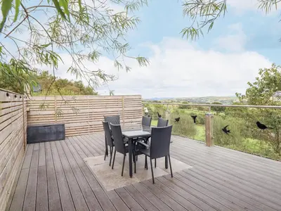 a wooden deck with a table and chairs on it at Hilltop Lodge in Corwen