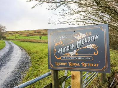 a sign for the hidden meadow on a road at Hilltop Lodge in Corwen