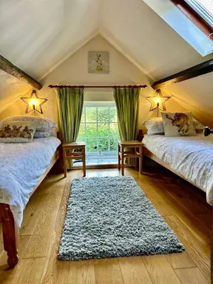 a attic bedroom with two beds and a rug at The Old Milking Parlour Flyingpiglets in Llandovery