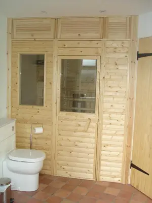 a bathroom with a toilet and a wooden wall at Kwerky Cottage in North Lydbury