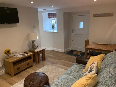 a living room with a couch and a flat screen tv at The Stables at Pentregaer Ucha, tennis court & lake in Oswestry