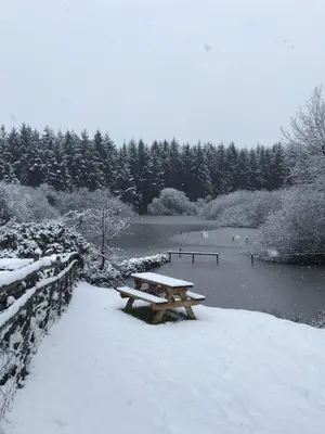 a picnic table in the snow next to a river at The Stables at Pentregaer Ucha, tennis court & lake in Oswestry