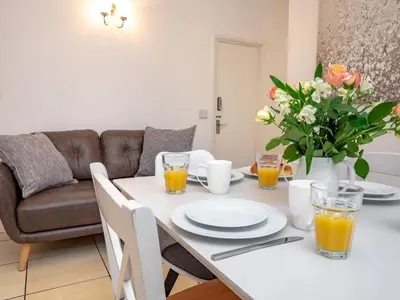 a white dining room table with orange juice and flowers at Pass the Keys 3 bedroom home within walking distance of town in Shrewsbury
