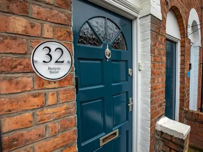 a blue door with a sign on a brick wall at Pass the Keys 3 bedroom home within walking distance of town in Shrewsbury