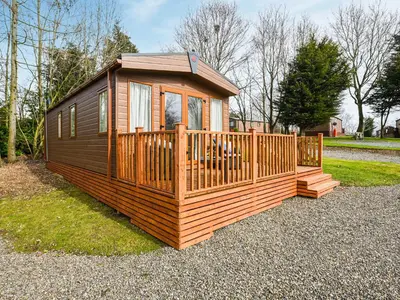 a large wooden cabin with a wooden deck at Avon Lodge in Hyssington