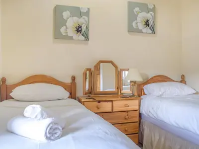a bedroom with two beds and a dresser with a mirror at Border View in Kington