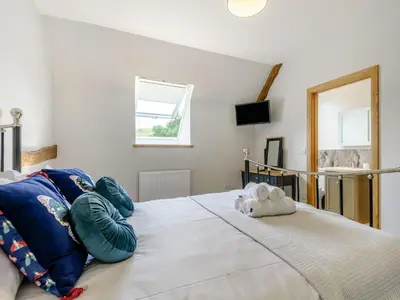 a bedroom with a bed with blue pillows and a mirror at Penshenkin Barn in Llanfihangel-nant-Melan