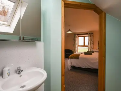 a bathroom with a sink and a bed in a room at Yr Hen Feudy At Pentre Farm in Llansilin