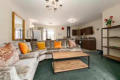a living room with a couch with orange pillows at The Granary, Bryncarnedd cottages in Aberystwyth