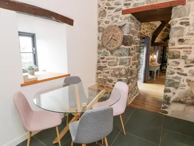 a dining room with a glass table and pink chairs at Beudy Bach in Llanbedr