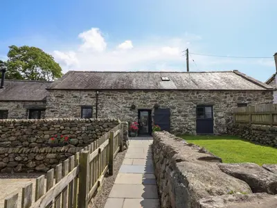 an old stone house with a stone fence at Beudy Bach in Llanbedr