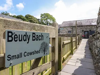 a sign for a small cottage on a wooden fence at Beudy Bach in Llanbedr