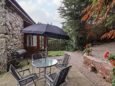 a table with chairs and an umbrella on a patio at Yr Hen Felin in Oswestry
