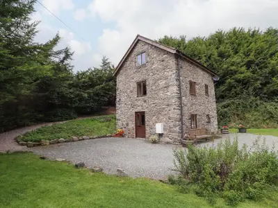 a stone house in a yard with a gravel driveway at Yr Hen Felin in Oswestry