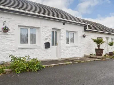 a white brick house with a white door and windows at The Snug in Aberaeron